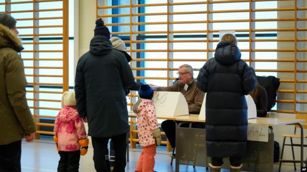 People receive their ballots at a polling station during a presidential election in Espoo, Finland, Feb. 11, 2024.