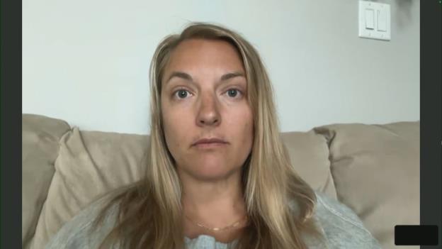 Blonde woman in grey shirt sitting on a beige couch